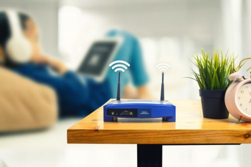 closeup-wireless-router-man-using-smartphone-living-room-home-office_36051-278